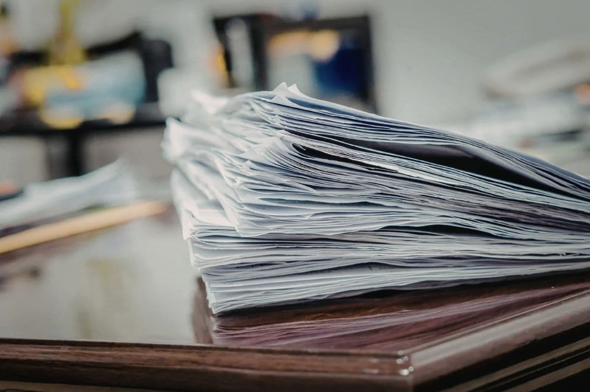Een stapel papieren rapporten op een bureau